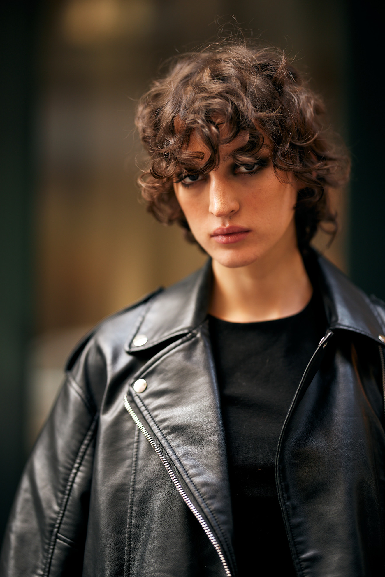 a woman with a brown curly bob and black leather jacket