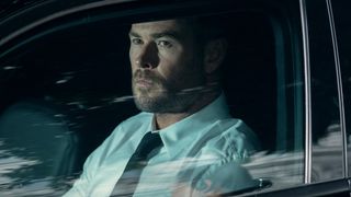 Chris Hemsworth's Davis looking out of a driver side's car window in Crime 101