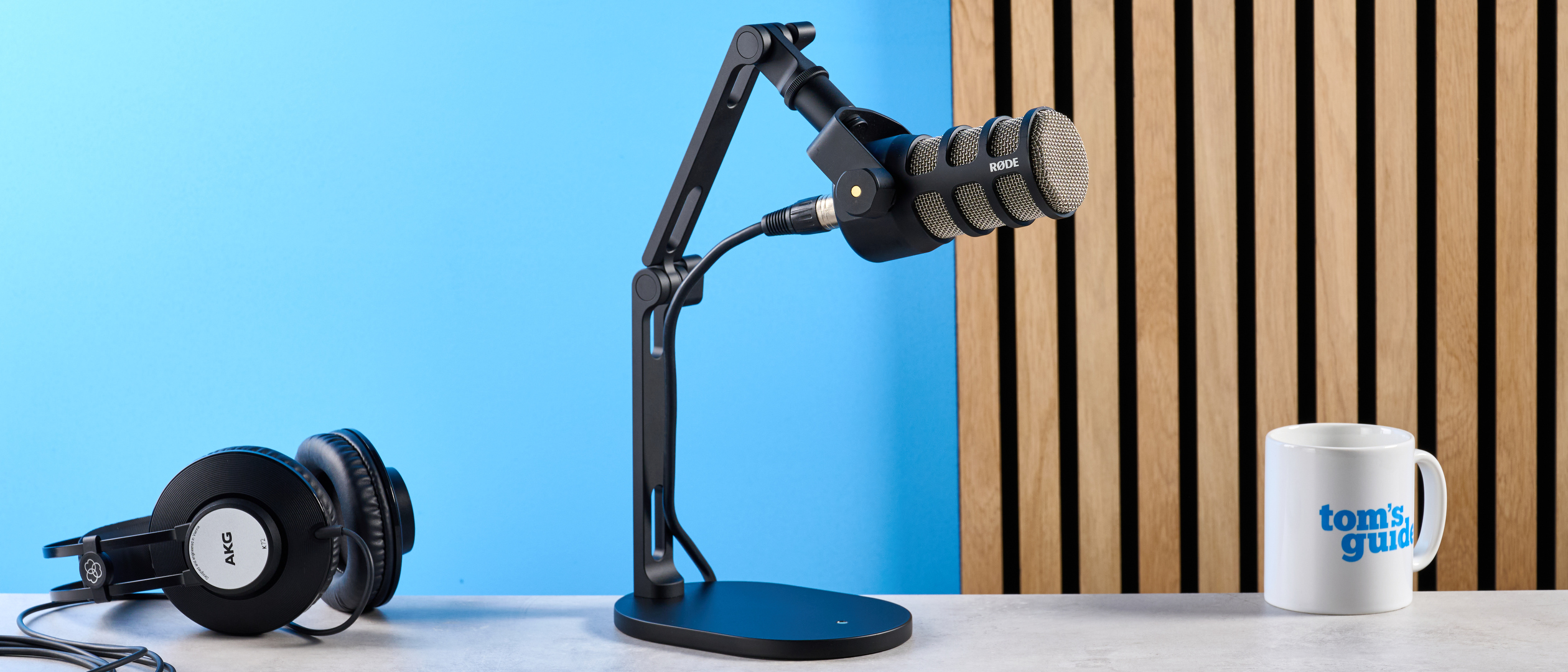 the rode podmic podcast and broadcast microphone photographed with a blue background, shown with the rode ds2 desk stand