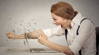 A furious woman punches through her laptop. screen.