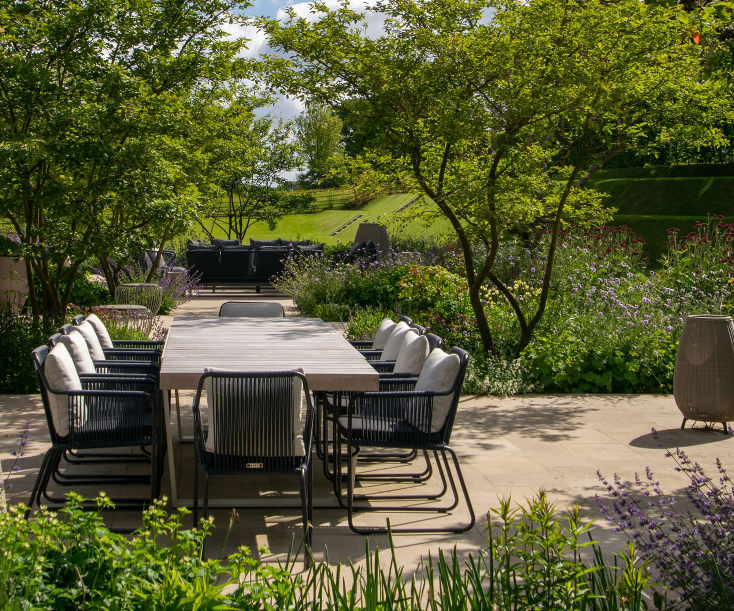 Outdoor dining area with black metal chairs and planting