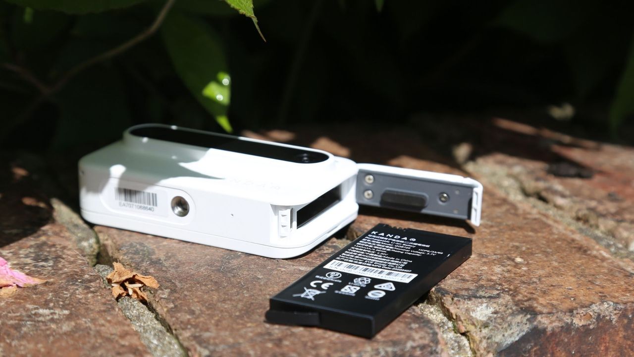 The Kandao Qoocam Ego 3D camera sitting on a brick wall with its battery removed