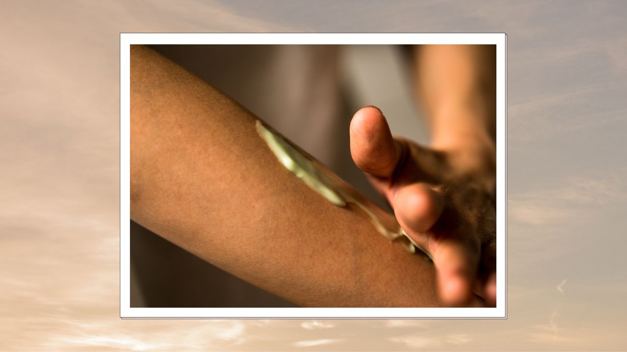 A close up of someone applying a cream product to the skin on their arm/ in a beige and grey sunset-like template 