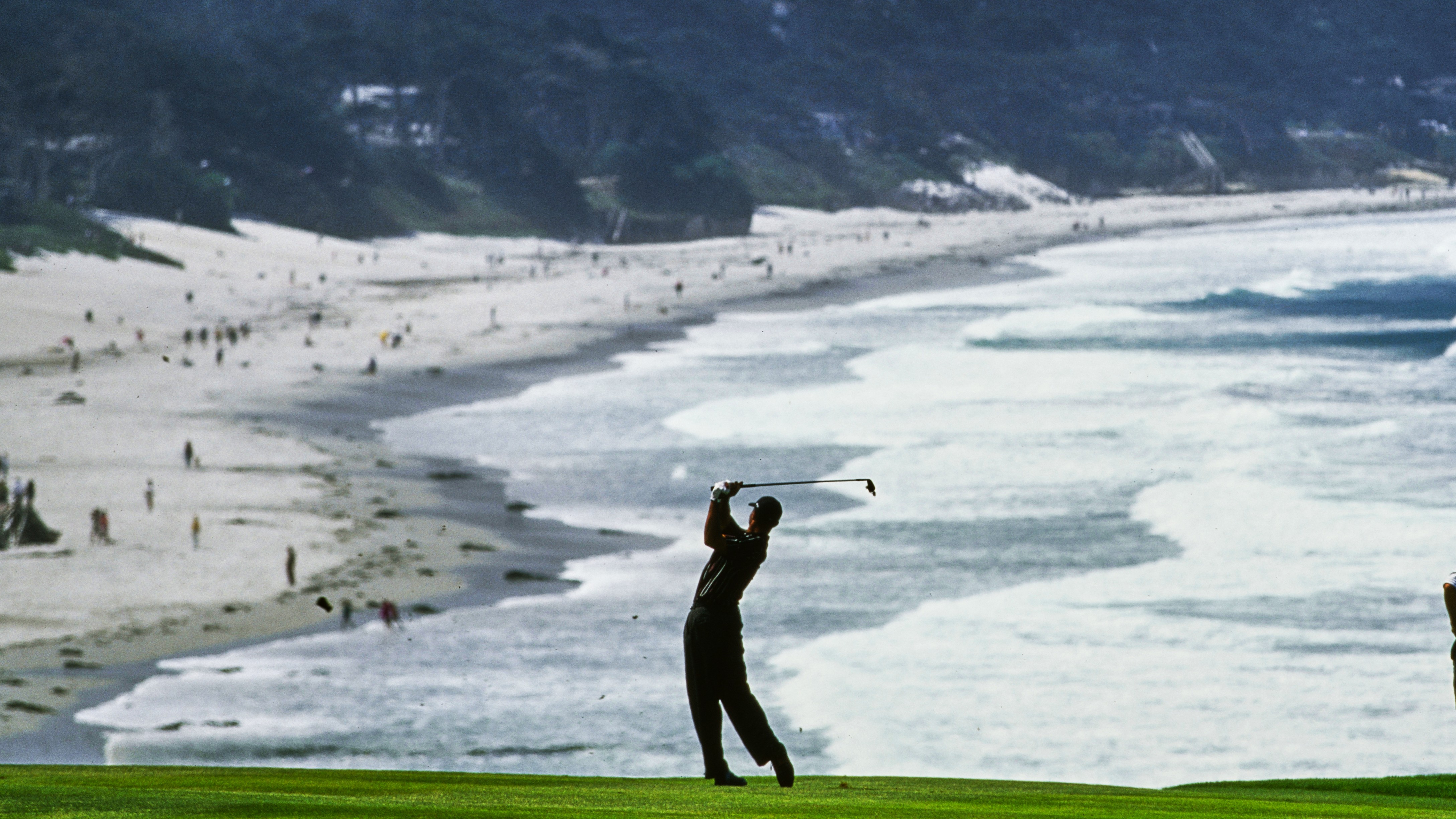 Tiger Woods against the backdrop of Carmel Beach playing an iron shot off the ninth fairway during the 100th United States Open at the Pebble Beach Golf Links en route to a winning record margin