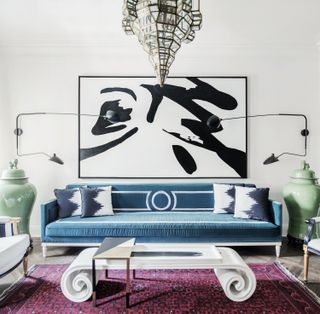 A turquoise sofa underneath a black and white painting