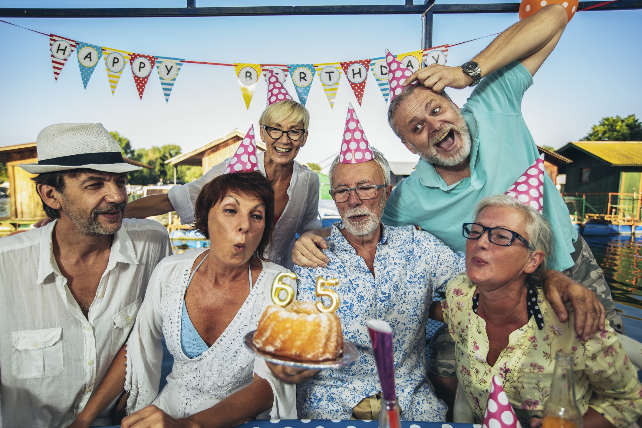 Senior people celebrating birthday in the cottage on the river having fun.