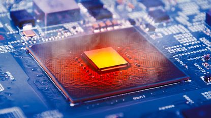 A close up of a computer processing chip, its center square bright yellow and the surrounding chip glowing orange and red with heat while the rest of the circuit board is a dark blue