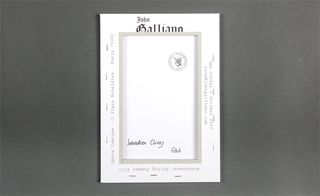 Back view of ﻿John Galliano's invitation pictured against a grey background