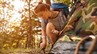 how to clean a pocketknife: camper using pocketknife on tent