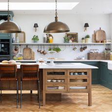 green kitchen with stone worksurfaces and wooden island