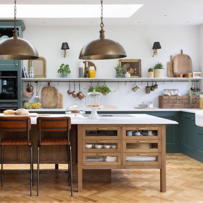 green kitchen with stone worksurfaces and wooden island