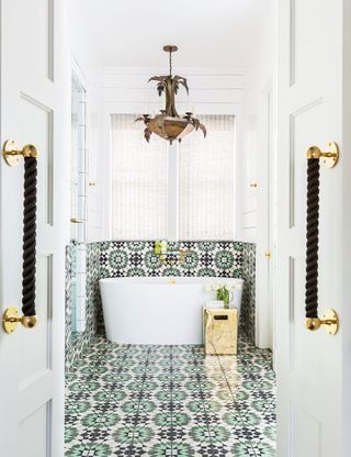 White bathroom with small tub and patterned wall and floor tiles