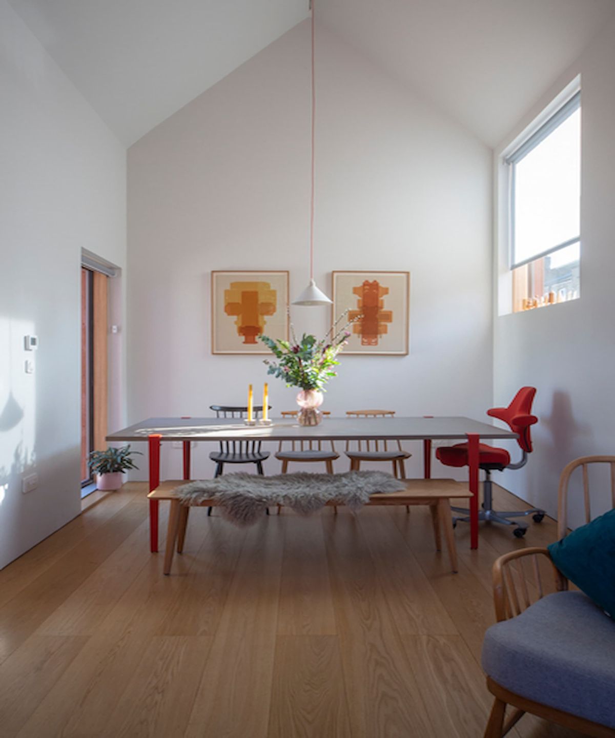 A dining room with white walls and a long dining table with a wooden floor
