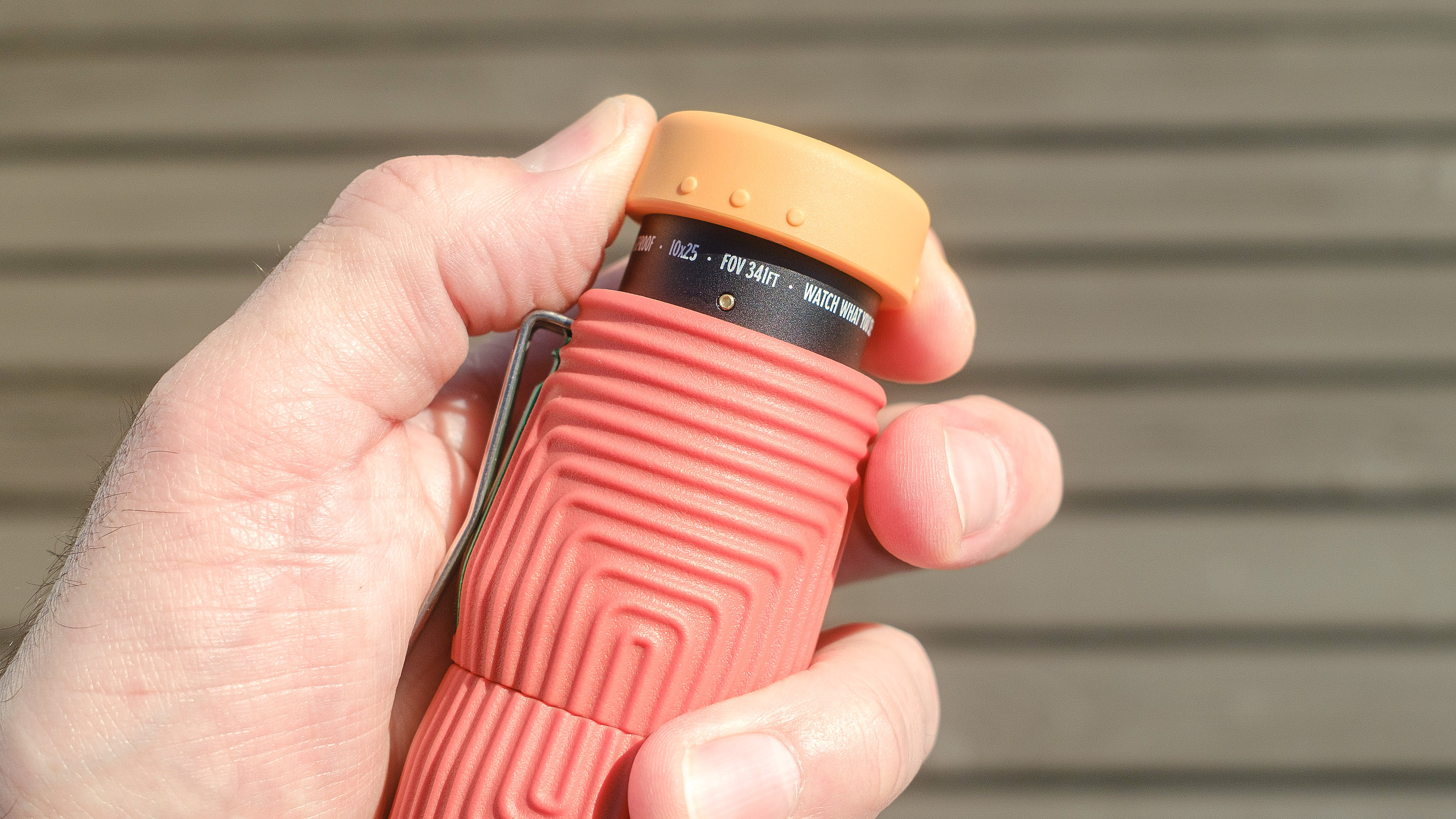 Nocs Zero Tube rugged monocular in orange shown close-up in a user's hand