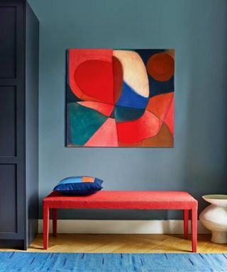 Blue room with bold red artwork and bench