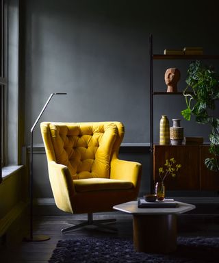 Butterscoth hued upholstery on button-back swivel, retro armchair, in contrast to dramatic dark charcoal scheme.