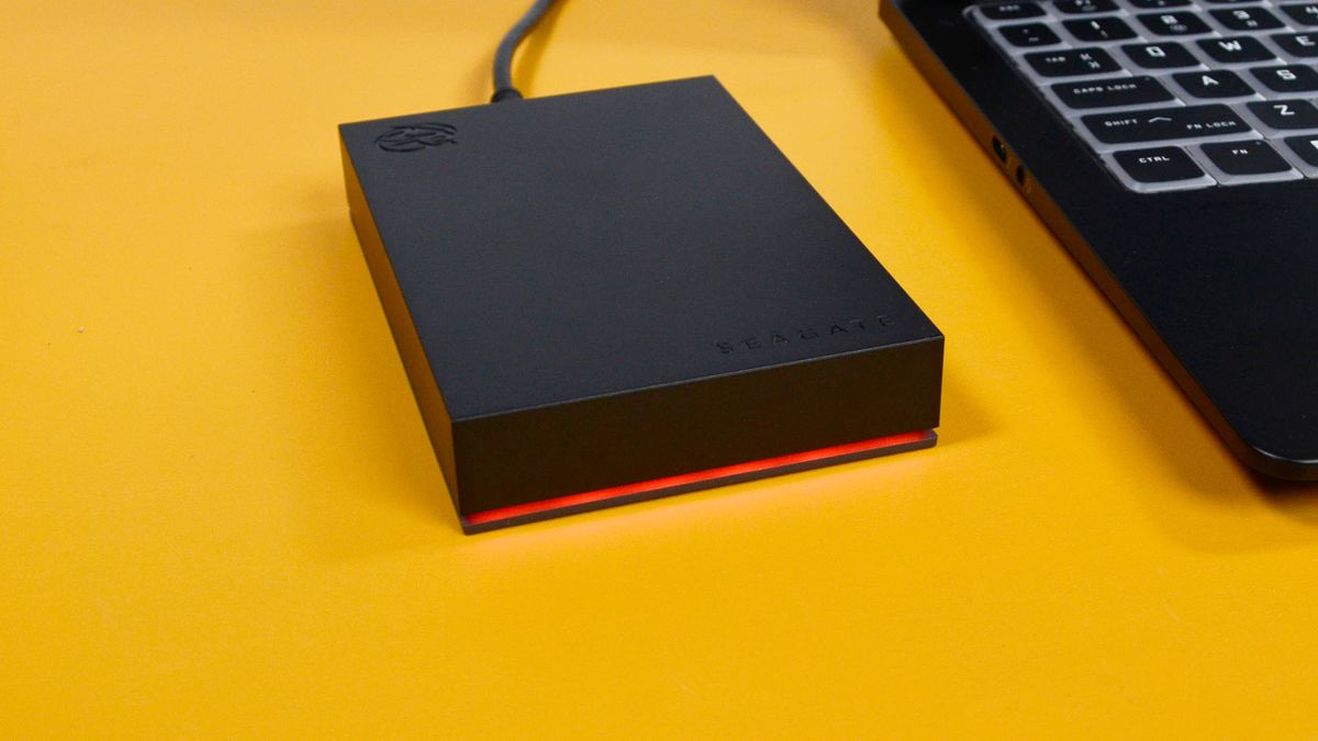 A Seagate FireCuda external gaming hard drive on a desk with a gaming laptop