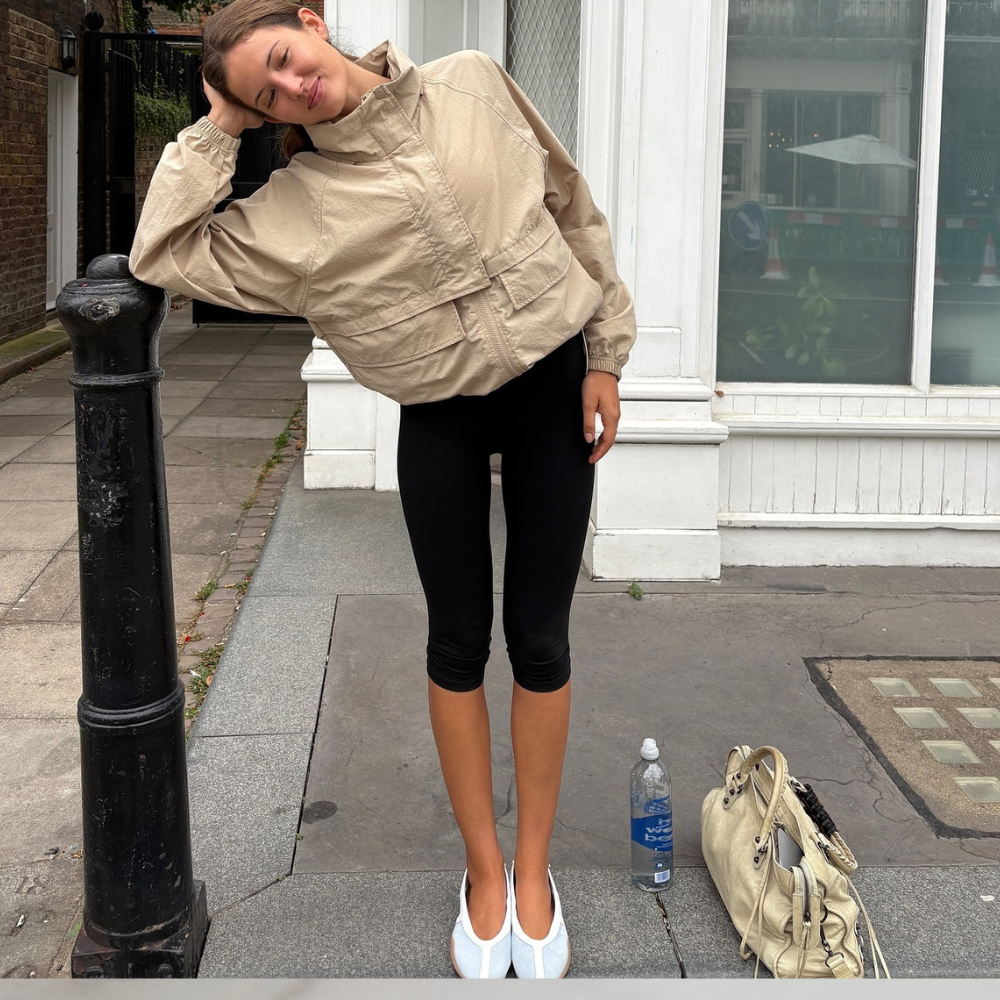 Fashion person Ruby Lynn wears a legging outfit 2025. She wears capri leggings, funnel neck beige jacket and adidas sneakerina.