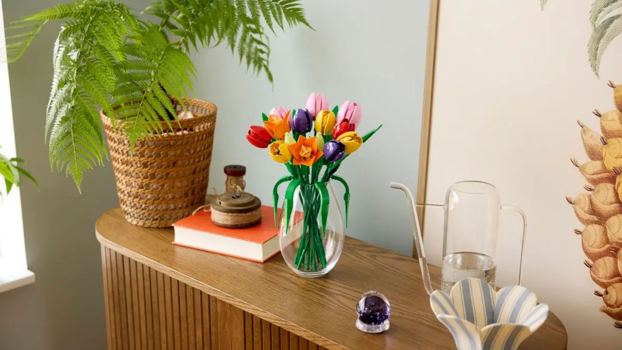 Lego Tulip Bouquet in a glass vase on a wooden sideboard, with plants and books beside it