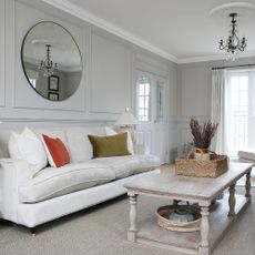 A grey living room with wall panelling, a grey rug and a cream sofa