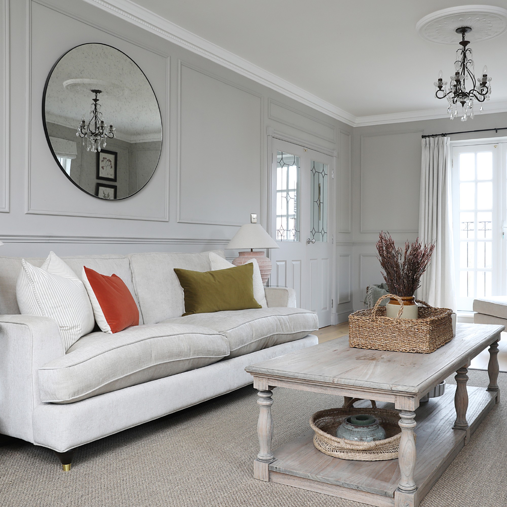 A grey living room with wall panelling, a grey rug and a cream sofa