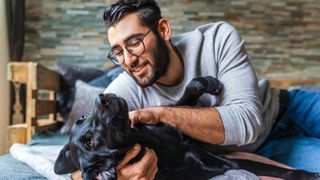 Man cuddling a dog on floor