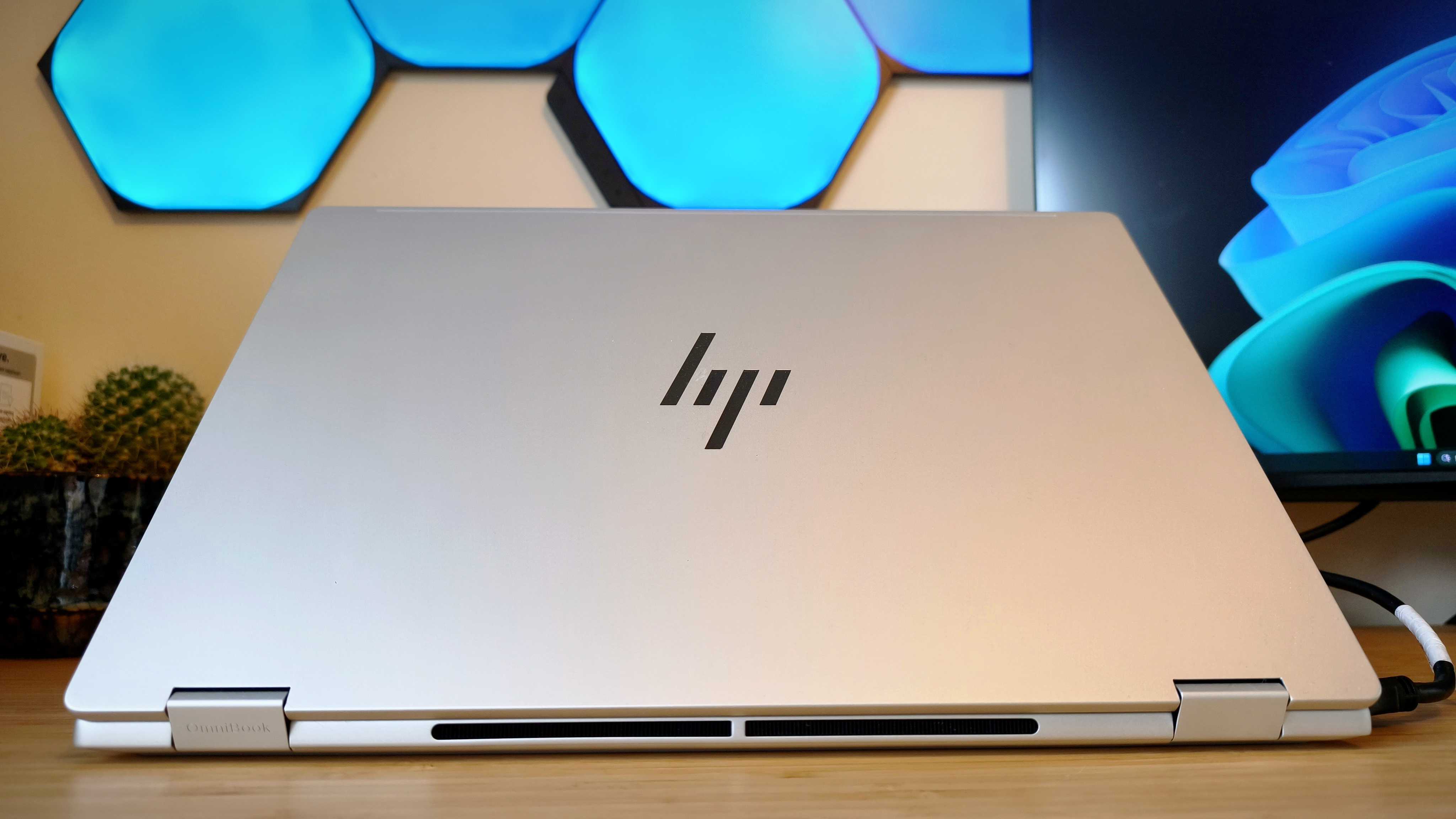A silver HP Omnibook X Flip 16 2-in-1 laptop on a wooden desk