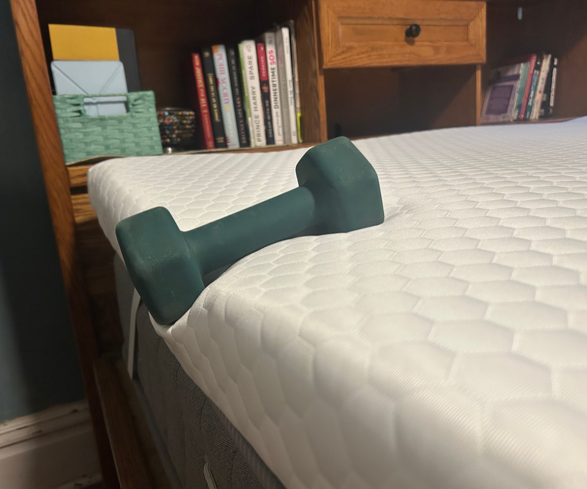 A dumbbell balanced on the edge of the Helix ErgoAlign Mattress Topper.