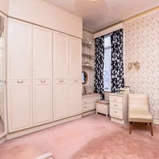 bedroom with cream wardrobes and floral wallpaper