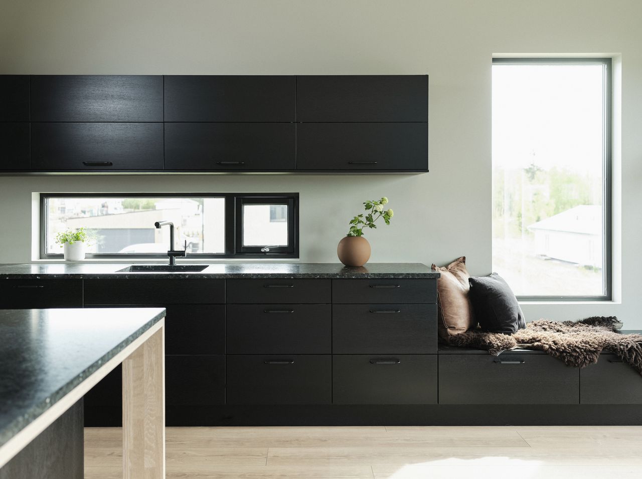 A dark themed kitchen with black cabinetry and bare countertops 