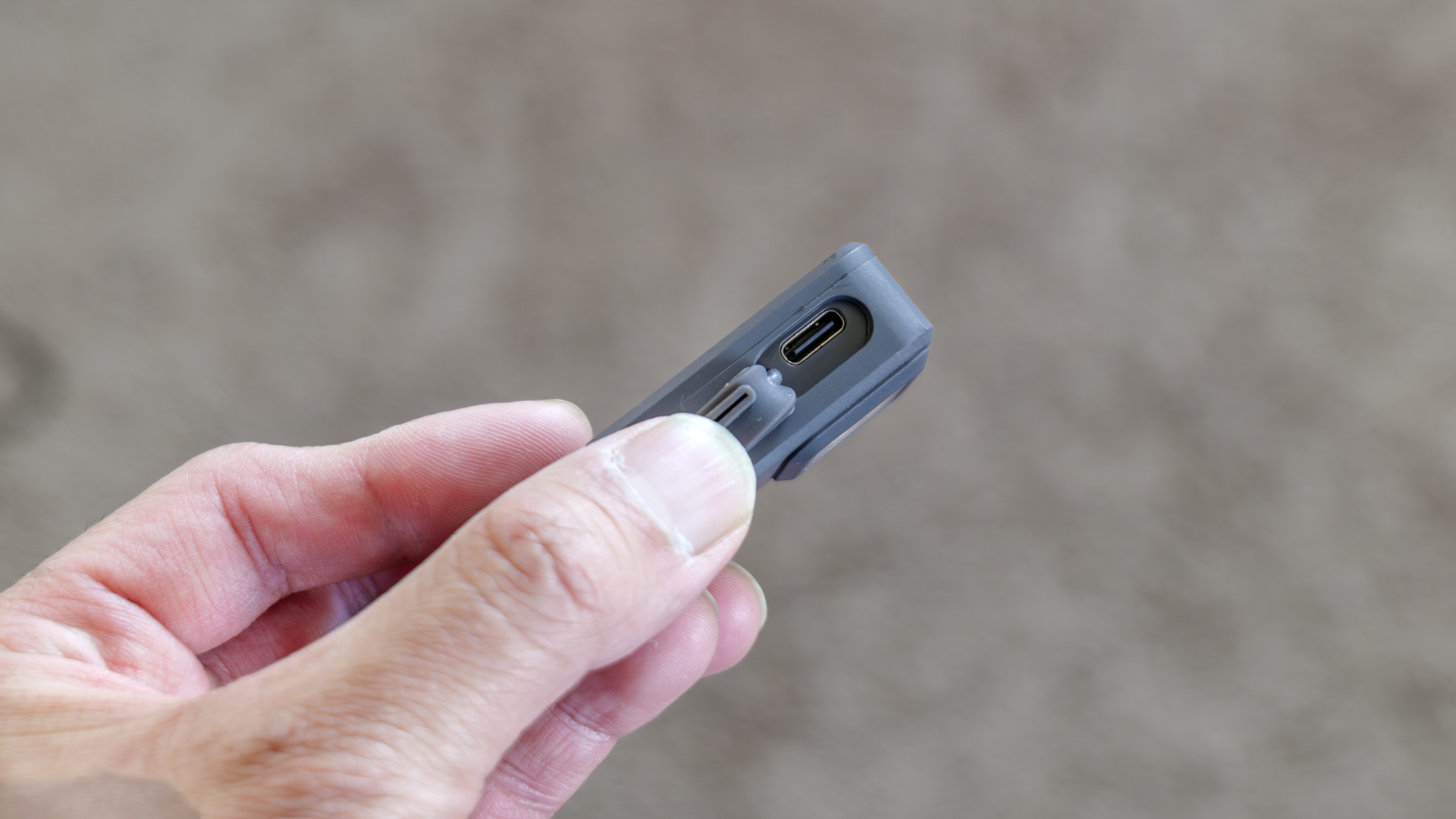 Pebblebee Halo held in the hand with USB-C port closeup.