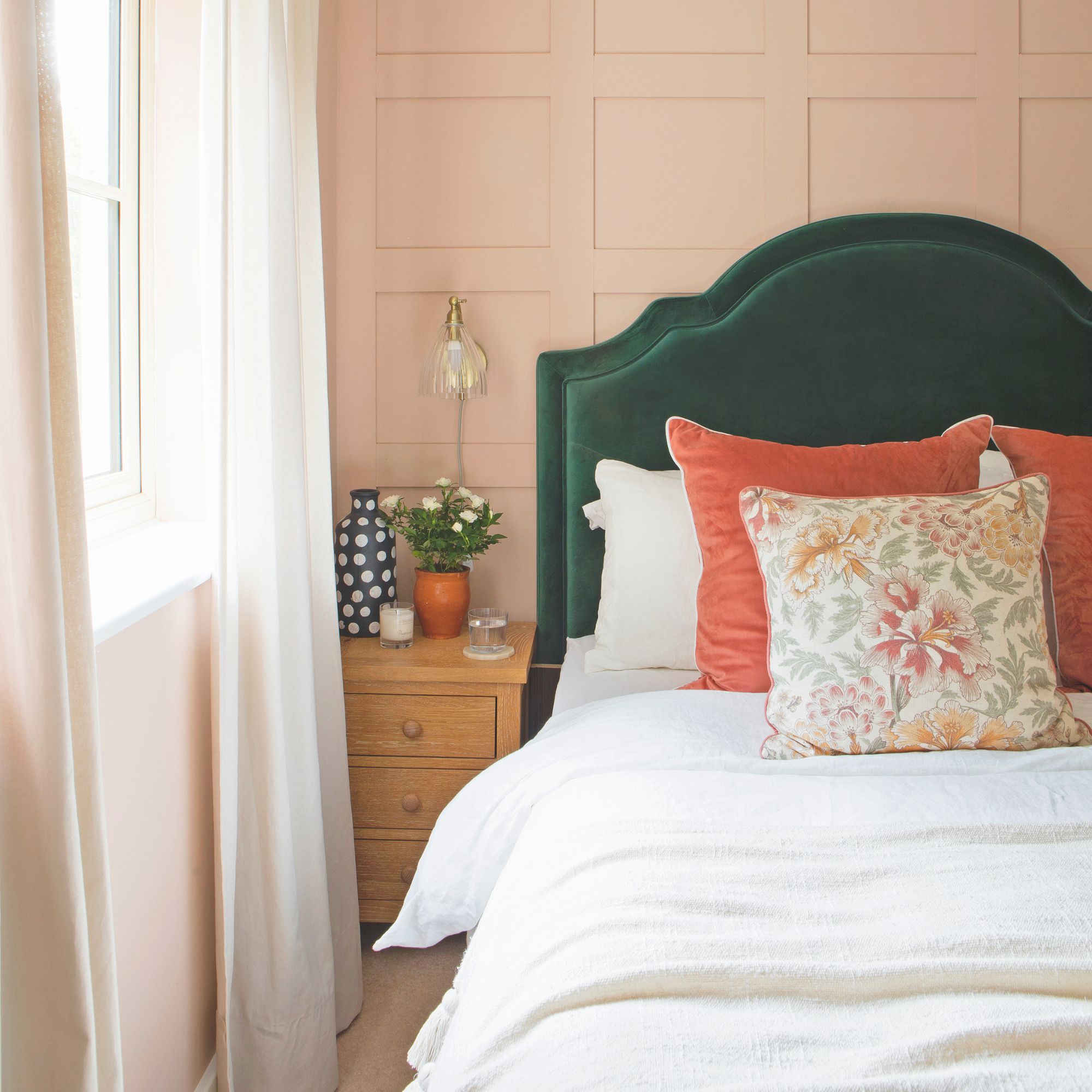 Bedroom with pink panelling behind it, and a green headboard next to a wooden bedside table