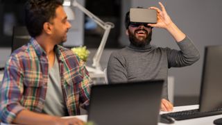 best laptops for game development: two game developers using a laptop and VR headset in an office