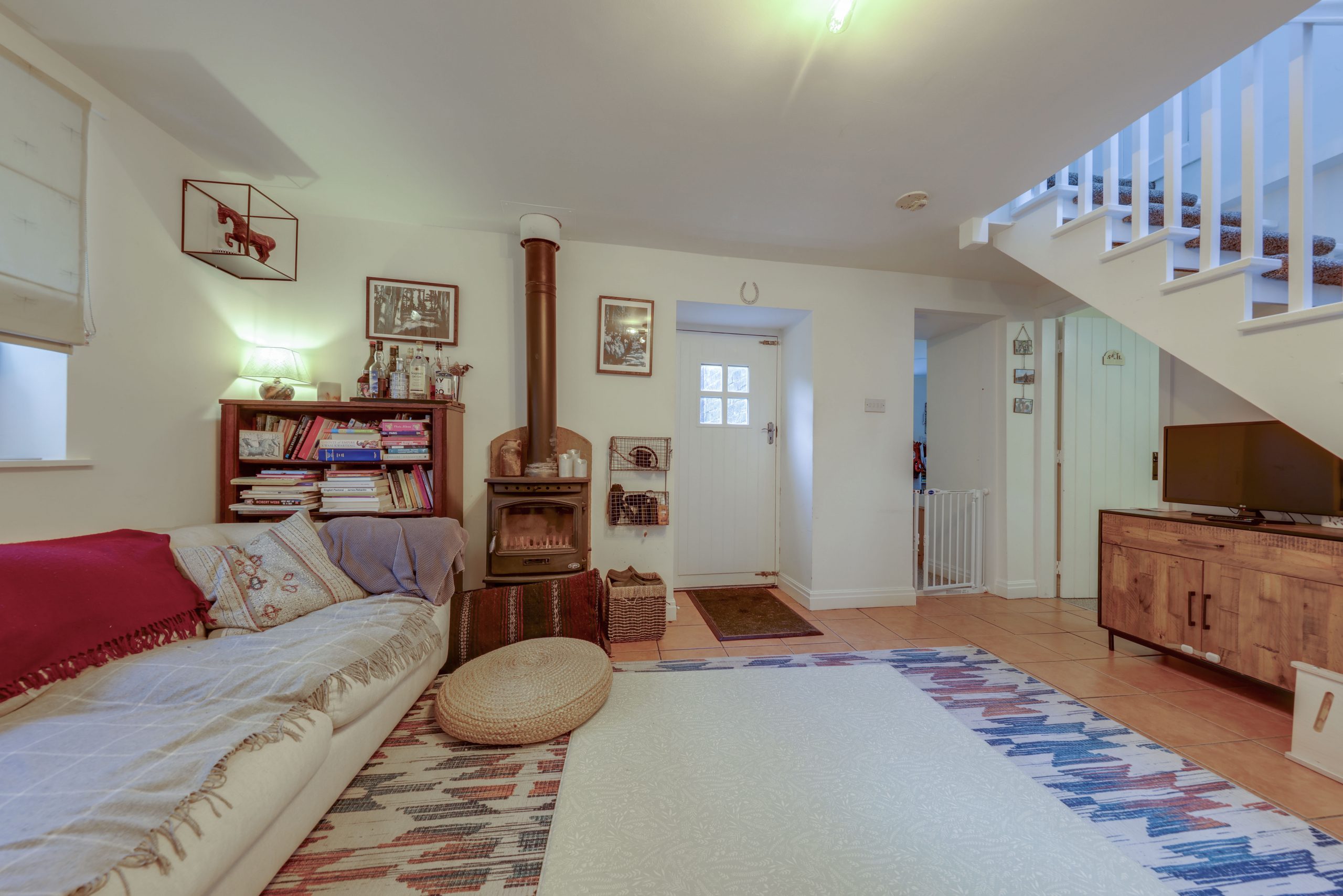 A sitting room with wood burning stove and stairs on the right
