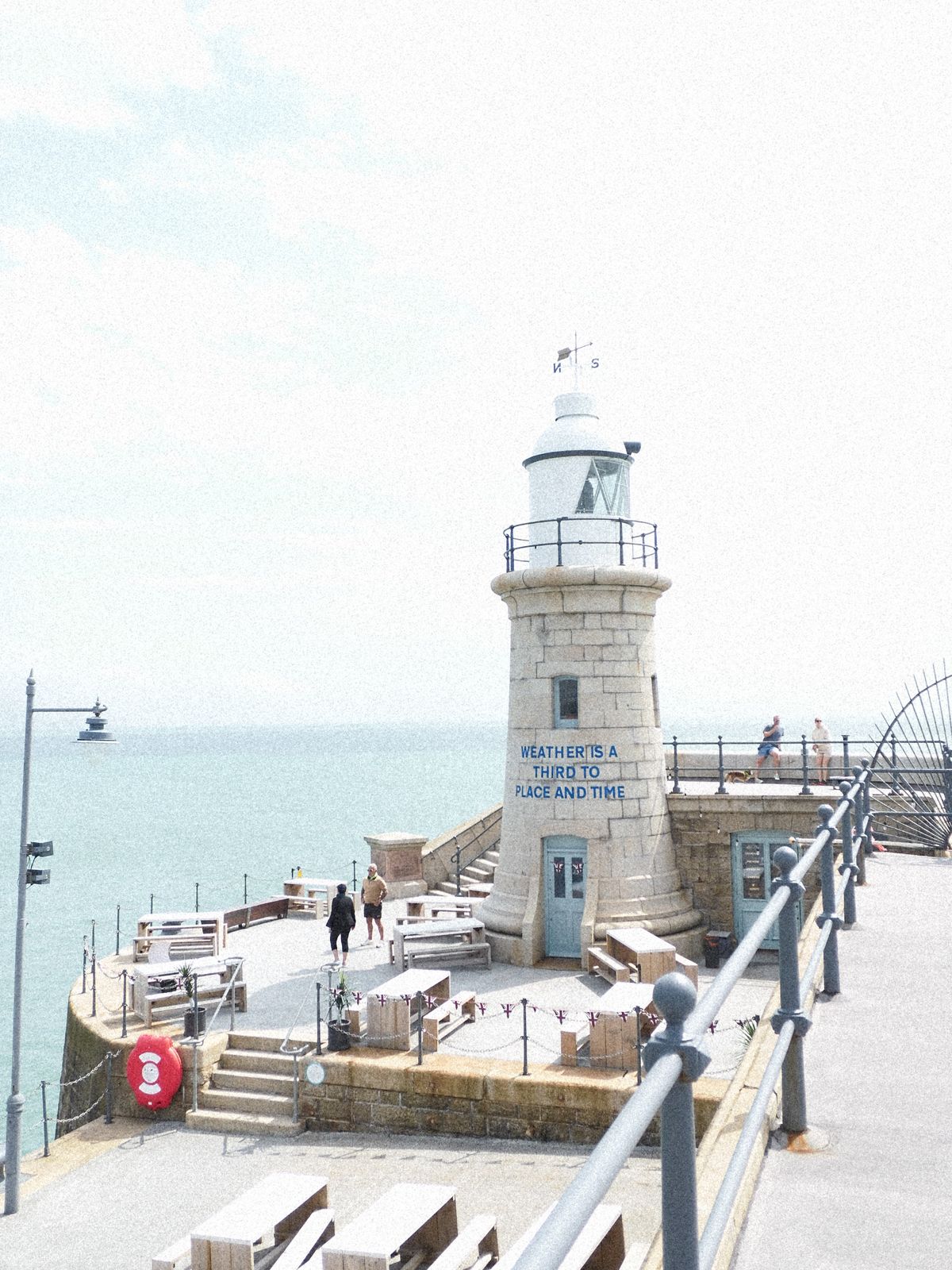 A lighthouse at the end of a pier overlooking the sea