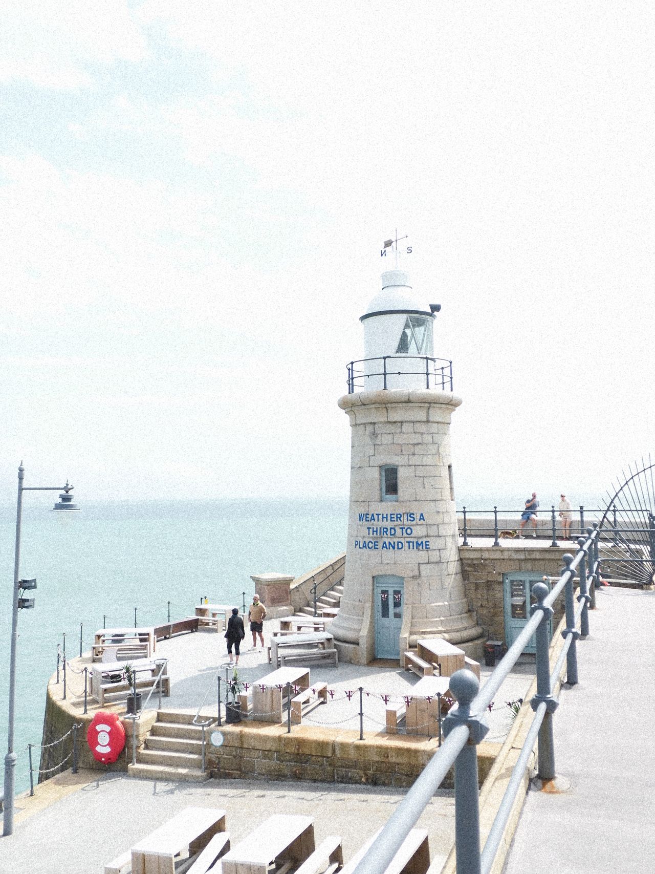 A lighthouse at the end of a pier overlooking the sea