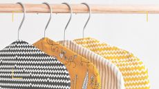 A wooden clothes rail with hangers with monochrome and yellow covers to illustrate Trinny's clothes rail styling tip