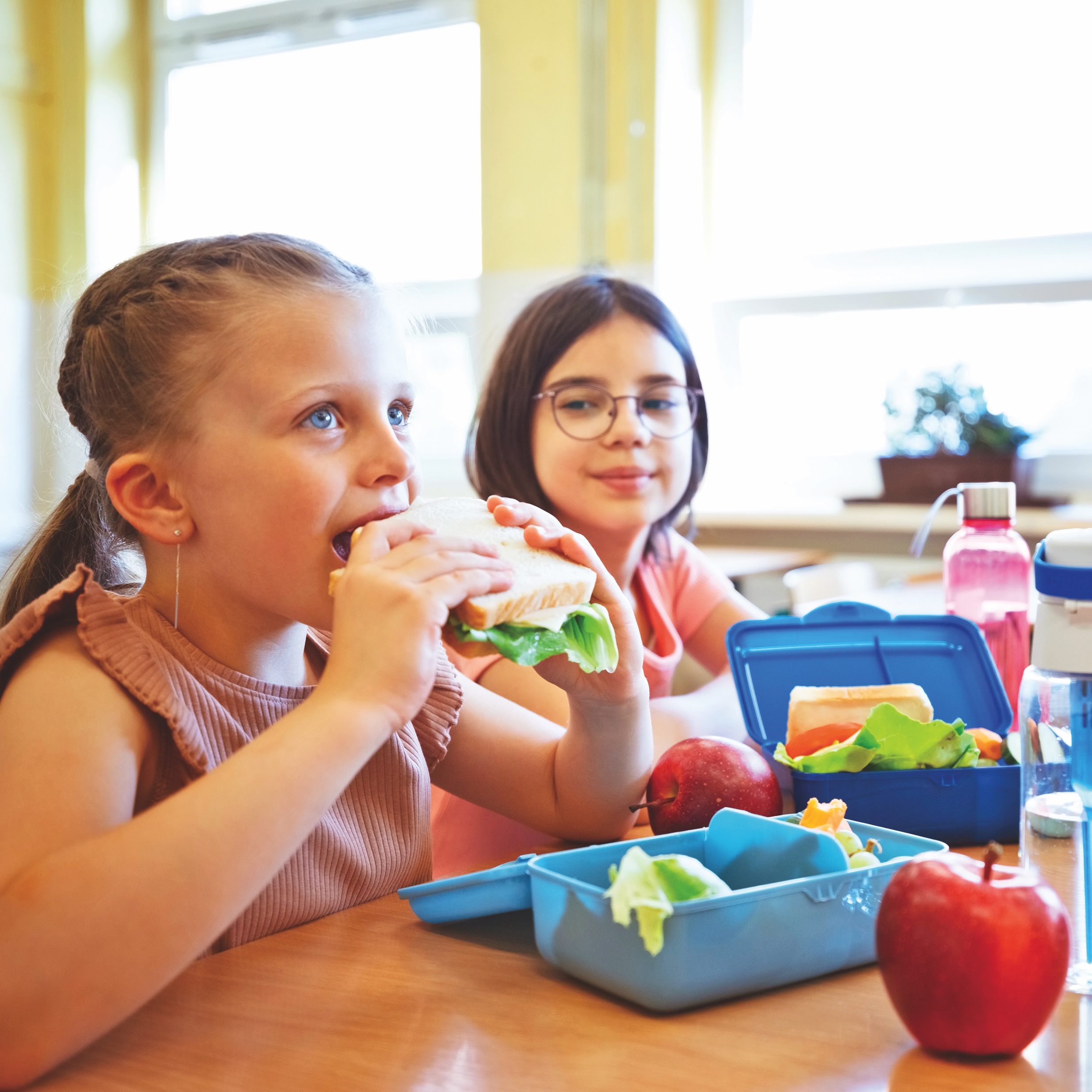 Two girls eating a packed lunch