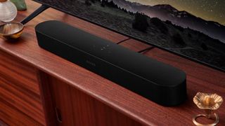A Sonos Bean 2 in front of a television and sitting on a shelf. 