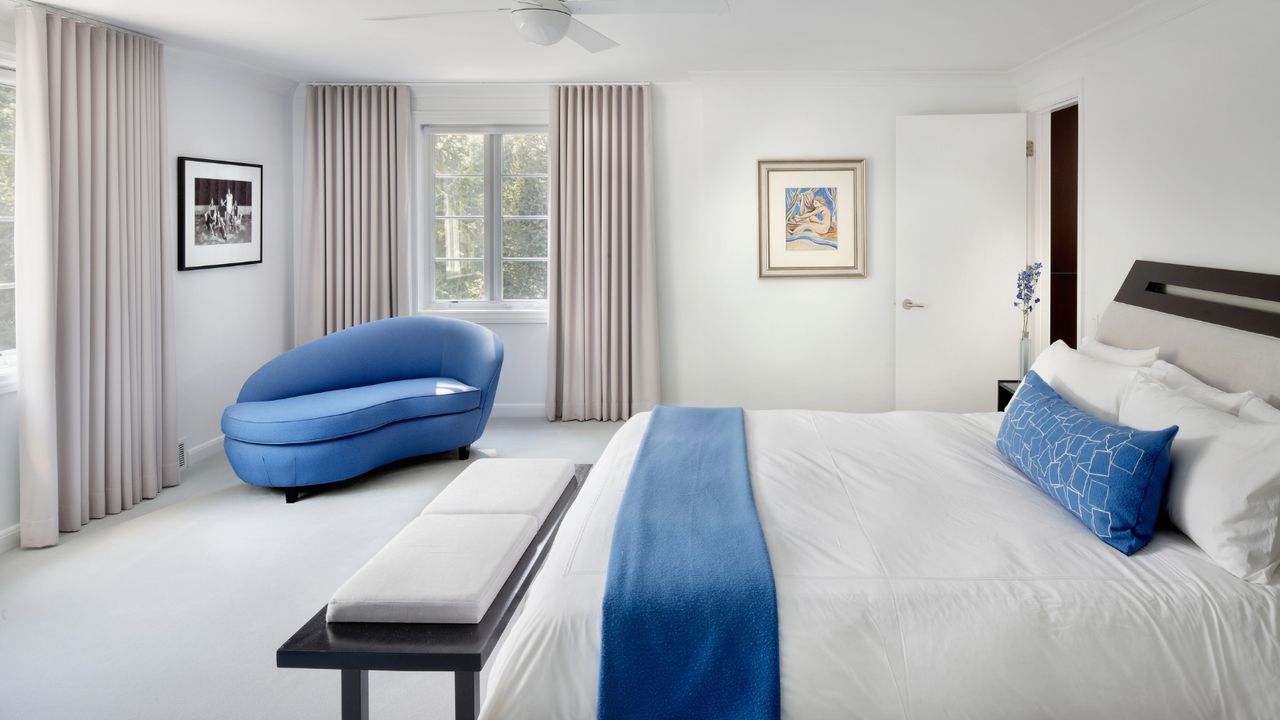 Tidy uncluttered modern master bedroom with blue pillows and through accenting love seat in Chicago IL