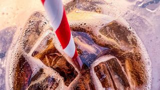 close up on a striped red and white straw inside a fizzy glass of diet soda