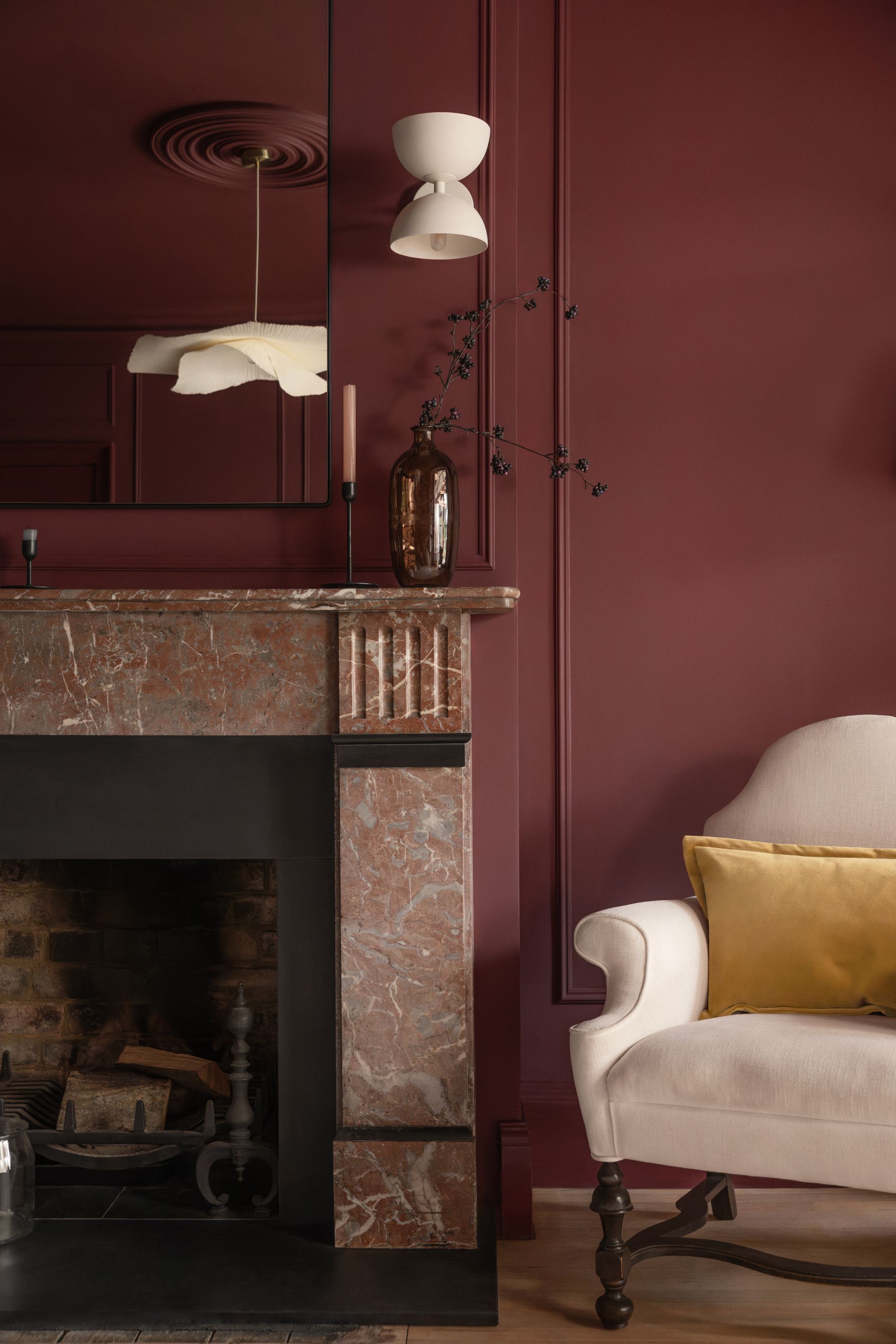 Image of a red living room with a red marble fire place and a cream accent chair in the corner.