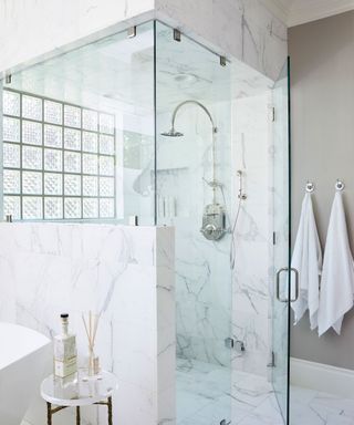 light and bright modern bathroom with marble floor and wall tiles, sectioned shower design with glass window,