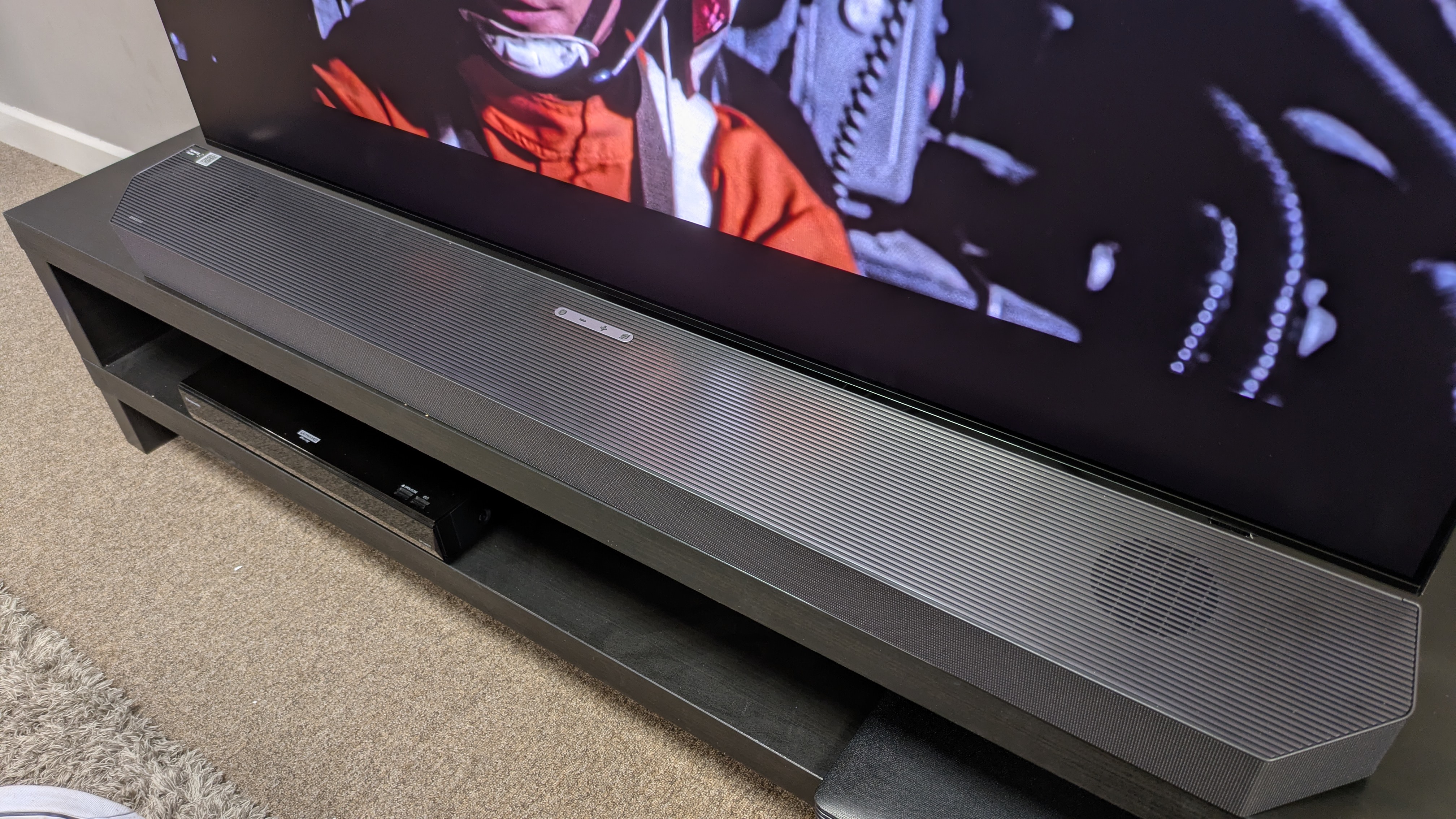Samsung HW-Q990H soundbar in front of Samsung S95F TV taken from side angle