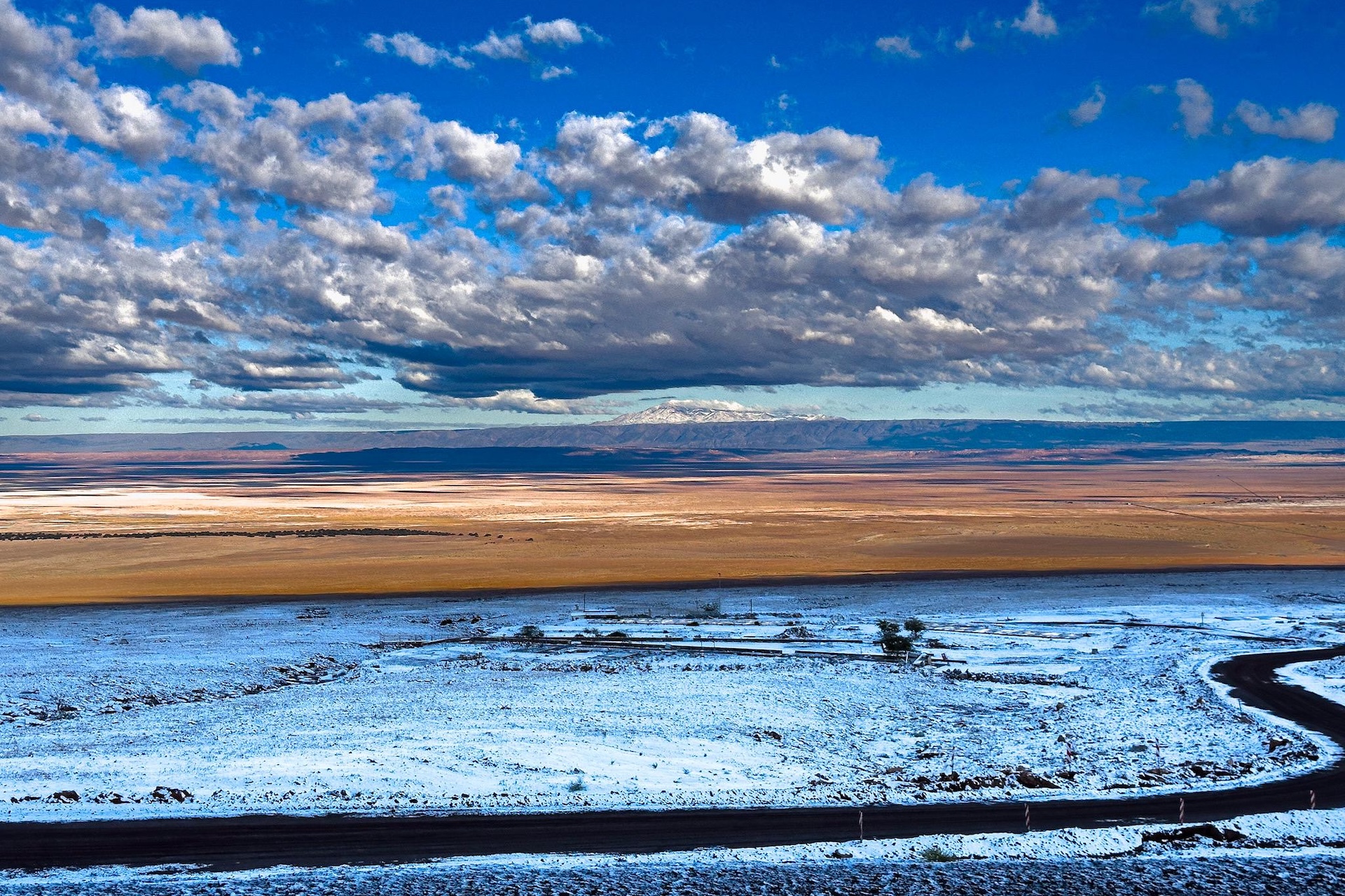 an image of snow blanketing the desert with clouds and a blue sky