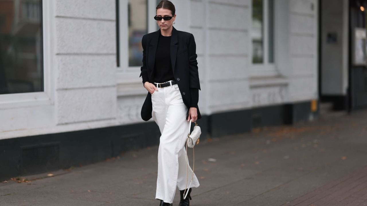 Woman in black blazer and white jeans GettyImages-1693364485 Hero