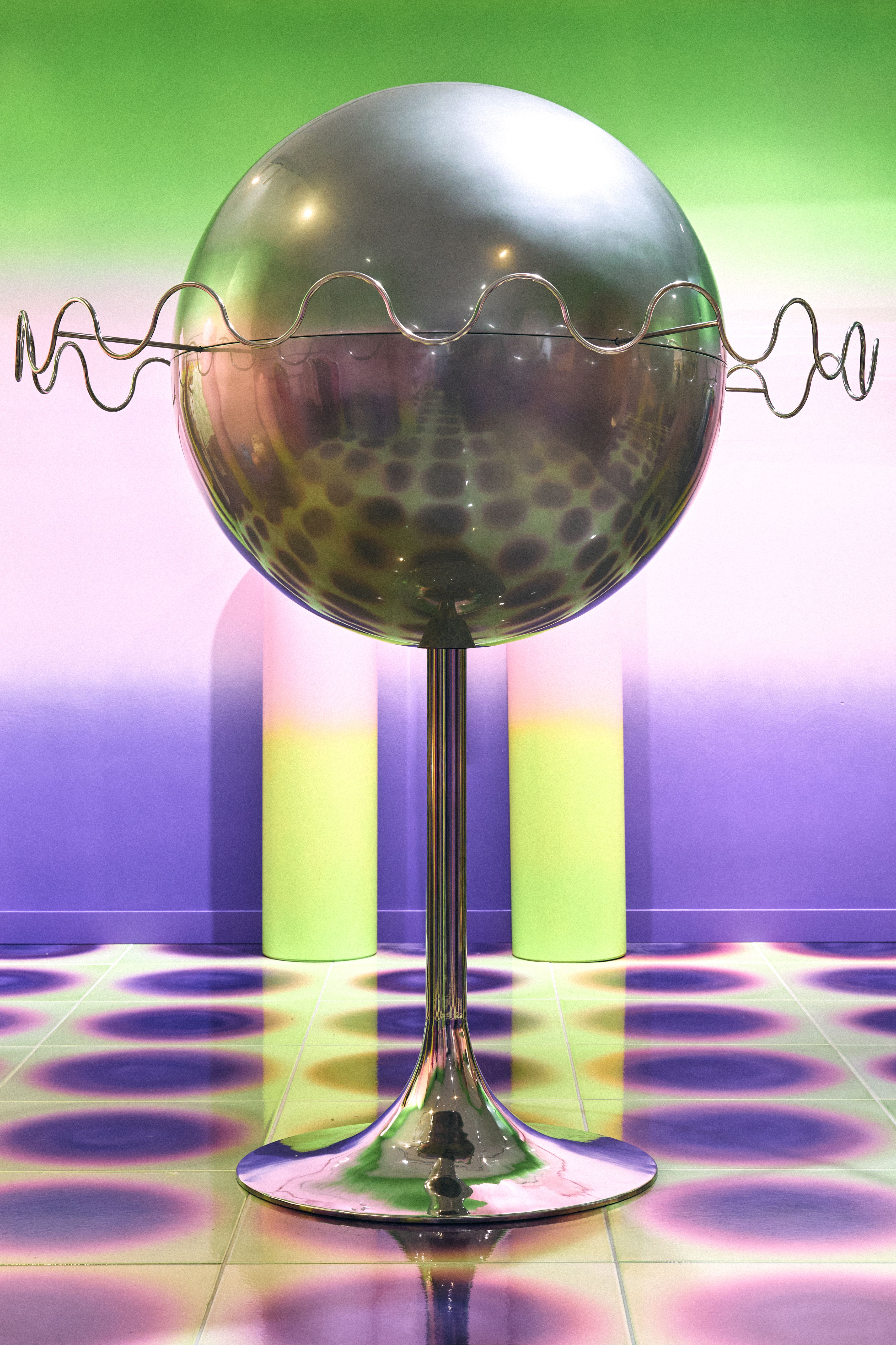 A concept store inspired by a 1960s, futuristic aesthetic features gradient tiles varying from electric green to pink and purple, chrome furnishings, and gradient purple walls leaning o lilac.