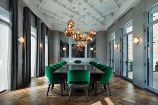 Dining room with grey walls, latticed ceiling, large dining table and green velvet chairs