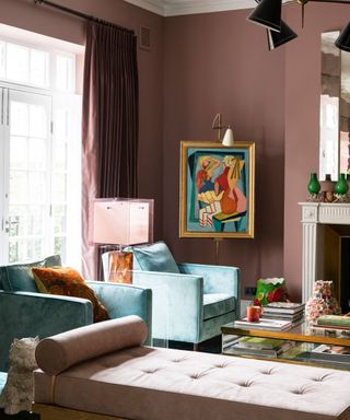 A living room decorated in pink and blue with abstract artwork and two blue chairs.