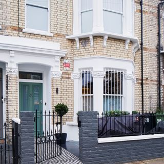 Exterior shot of six-bedroom Victorian Terraced home in Fulham, southwest London with dark green door and decorative black fence decor